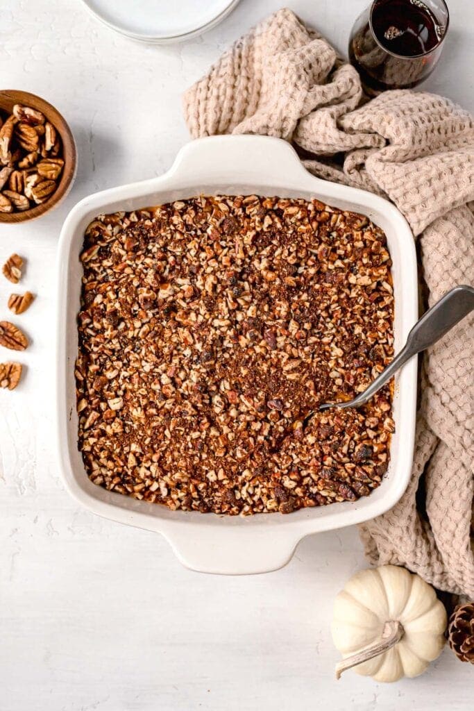close up of paleo sweet potato casserole in a white baking dish with a spoon in the top to serve