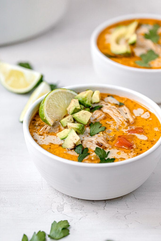 a bowl of white chicken chili garnished with a lime wedge