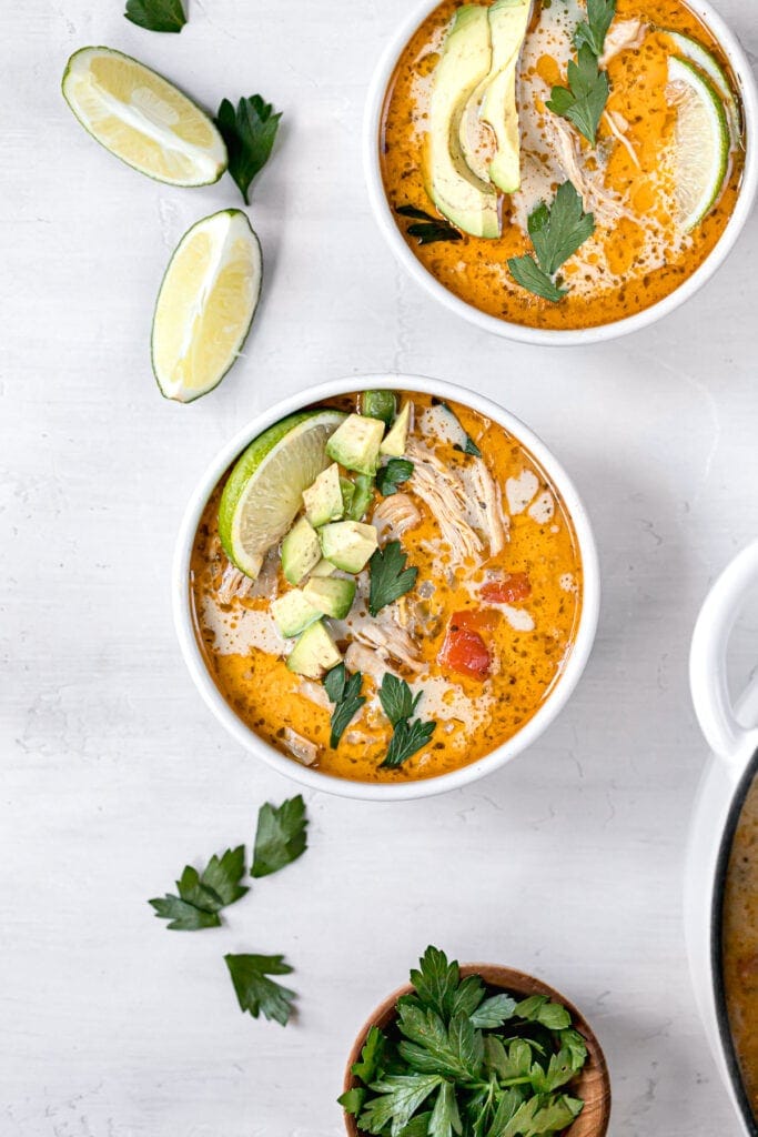 two bowls of white chicken chili next to garnish