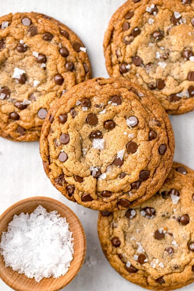 large dairy free chocolate chip cookies next to a bowl of sea salt