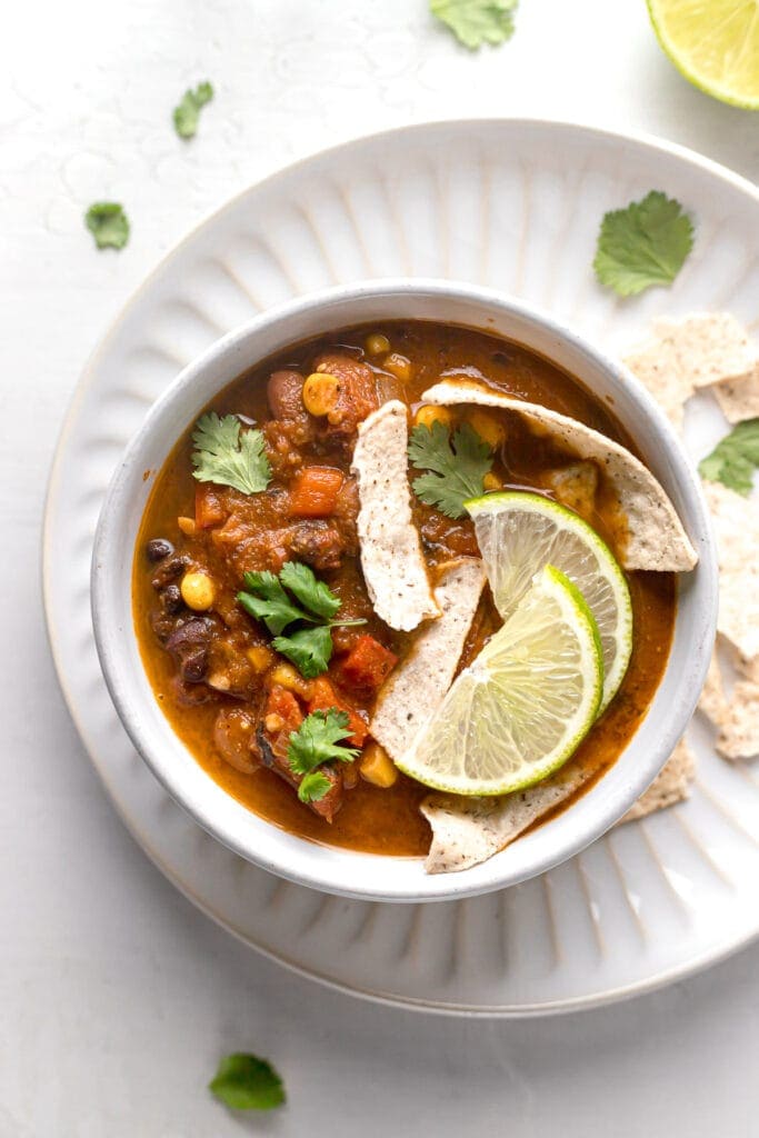 top view of vegan taco soup in a bowl with tortilla strips and lime wedges