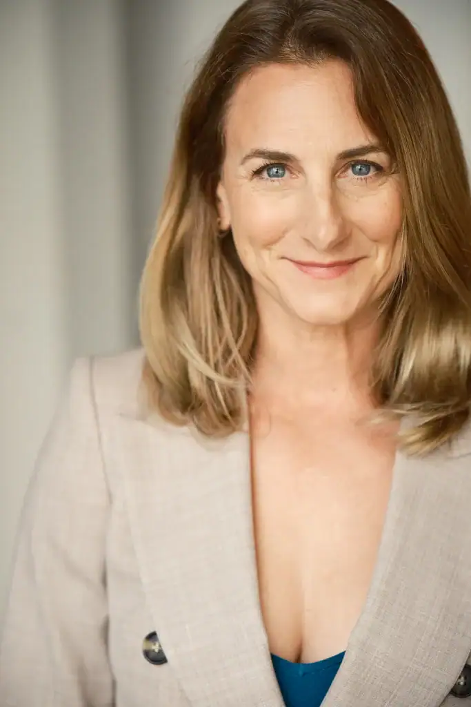 Portrait of a woman with blonde hair and blue eyes, smiling.