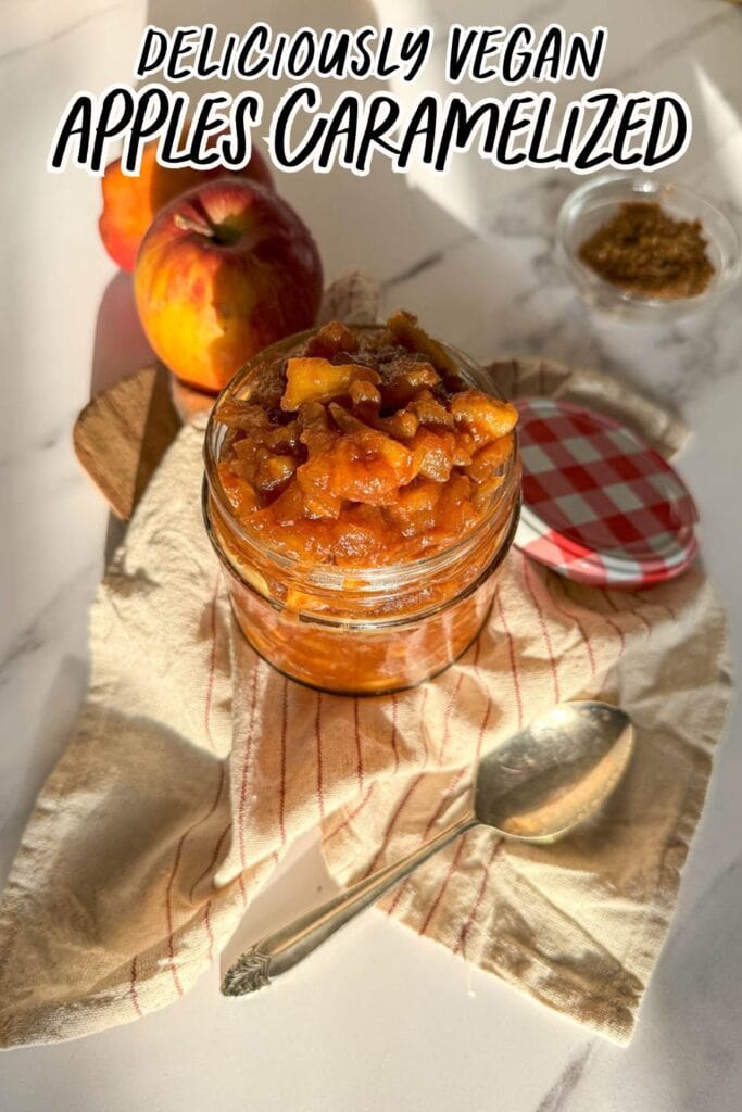 Delicious Apples Caramelized With Cinnamon And Brown Sugar, Vegan & Easy 8 Overhead shot of a jar filled with apples caramelized with cinnamon and brown sugar. Two whole apples, a checkered jar lid, a spoon, and a small bowl of brown sugar are arranged on a beige-striped cloth over a marble countertop.