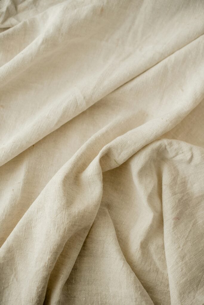 Close-up of crumpled light beige fabric with visible texture and folds.