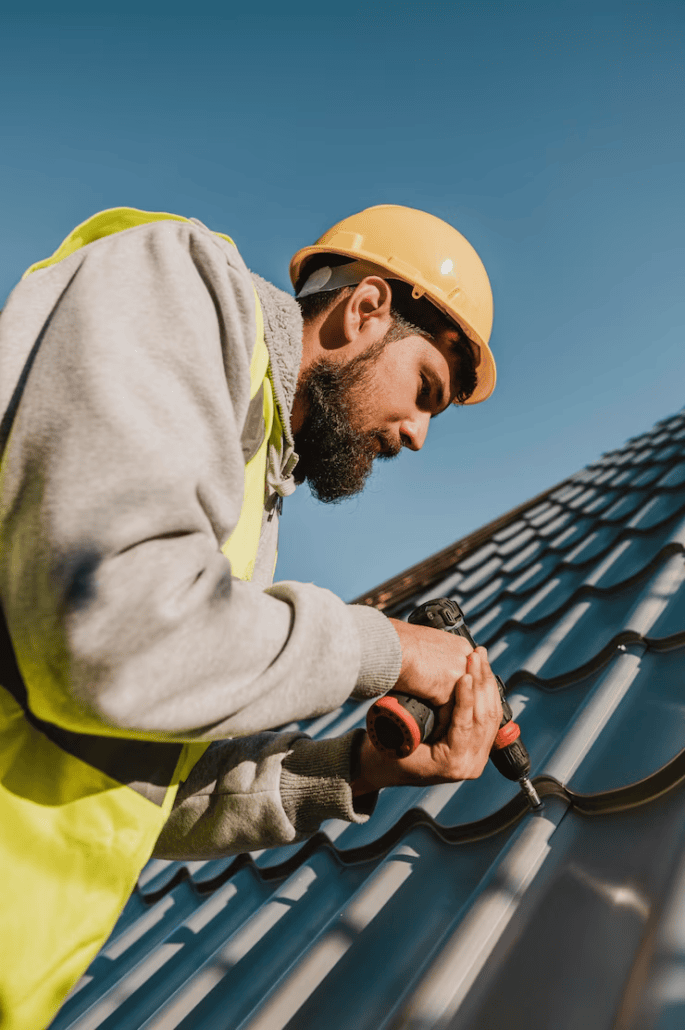 An expert roofer drilling while working on the installation of a roof. Get an estimate today by getting in touch with us.
