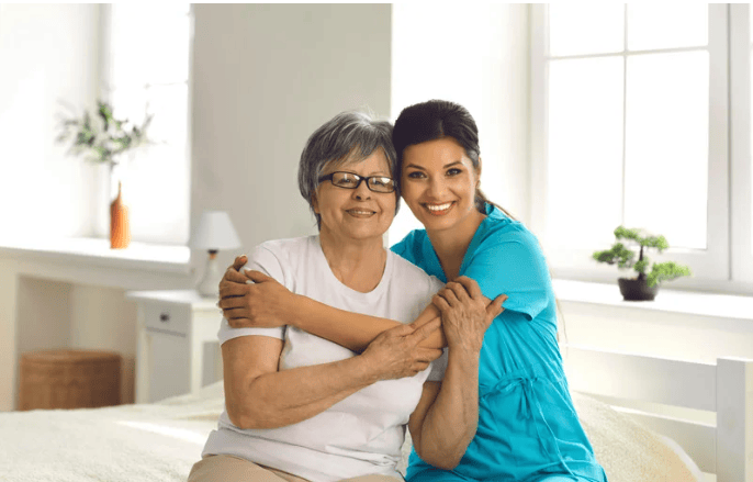 Happy hispanic elderly woman hugging her happy homecare worker