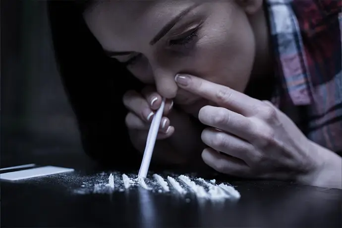 Girl snorting cocaine through a rolled bill, representing substance abuse