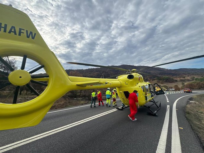 Helicóptero de emergencias en una carretera de Navas del Rey, con personal médico atendiendo la situación tras un accidente.