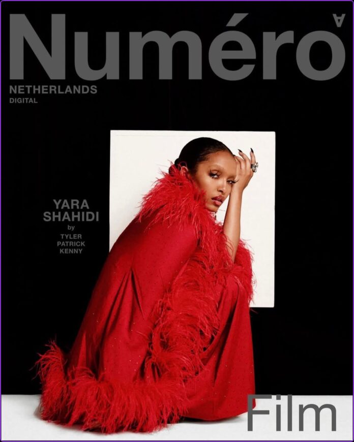 Yara Shahidi crouches in front of a white backdrop wearing black attire with red feathers for the Numéro Netherlands June 2026 cover.