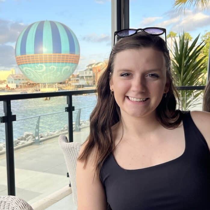 Vibrant woman enjoying waterfront view with hot air balloon in background, outdoor dining at 407 and Beyond Vacation Co.