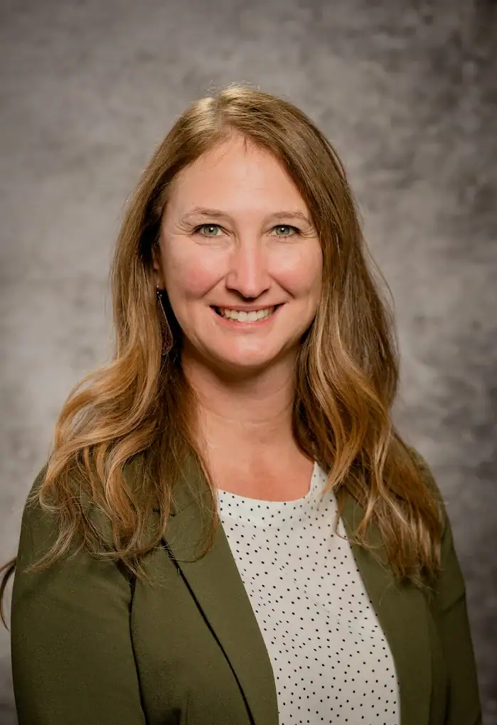 marcie connell wearing a white shirt, a green blazer and smiling at the camera