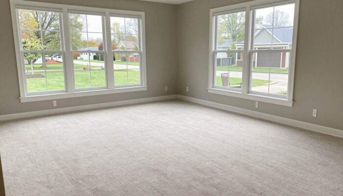Spacious living room with large windows and fresh carpet in Burlington, WI.