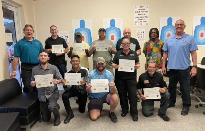 Students holding up their security guard certificates from All Florida Security Services