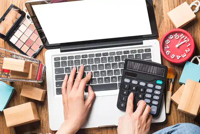 Laptop with calculator and office supplies on wooden desk, representing cloud software solutions and digital business tools.