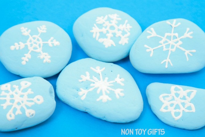 light blue painted stones with a white snowflakes drawings