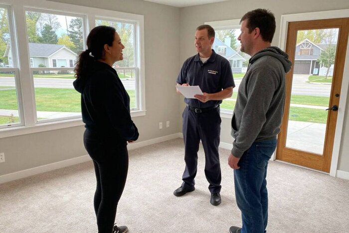 Professional carpet cleaners discussing cleaning services with clients in a bright living room.