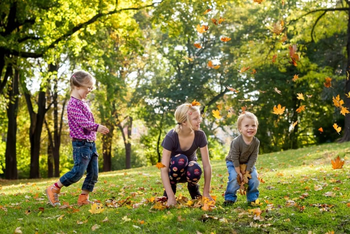 ein Familienbild mit 3 fröhlichen Kindern die im Herbst mit bunten Blättern spielen, fotografiert mit dem Canon 50mm f1.4 in Erfurt