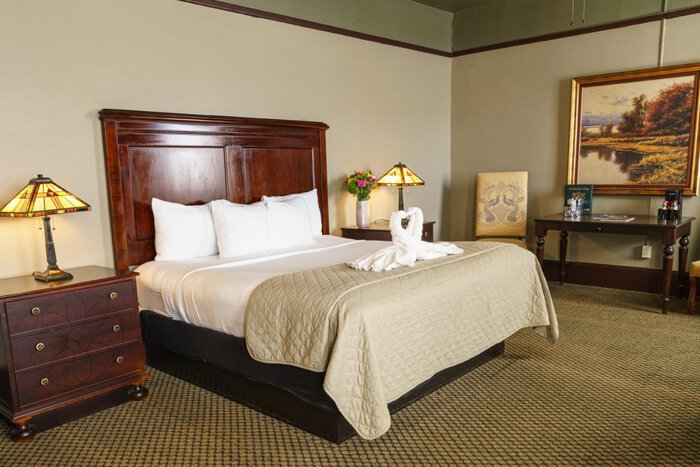 A cozy hotel room with a large bed, wooden headboard, and elegant decor.