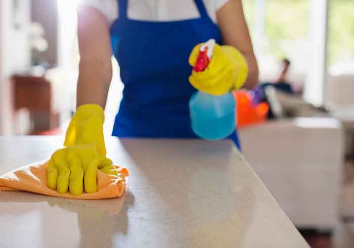 empleada del hogar limpiando una mesa.