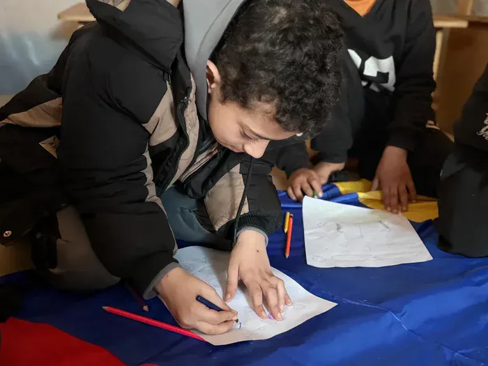 Kareem, 10, writing at the Temporary Learning Space