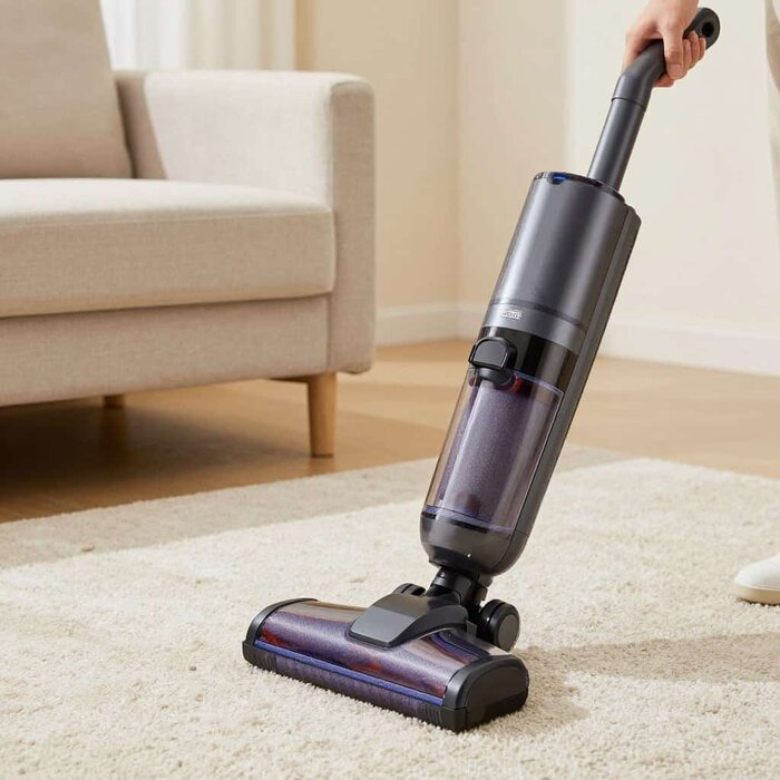 Modern vacuum cleaner cleaning a carpet in a living room.