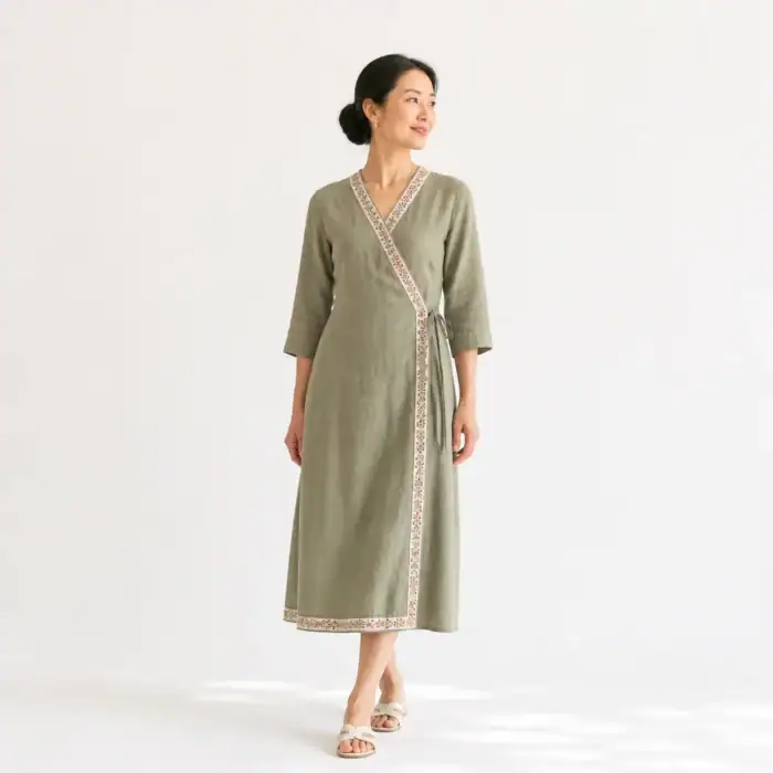 Woman in a sage linen wrap dress with a block-printed border