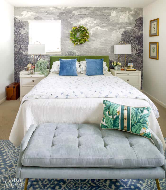 Blue and Green bedroom with lots of white and a wreath over the bed. Wall mural behind velvet headboard and white side tables.