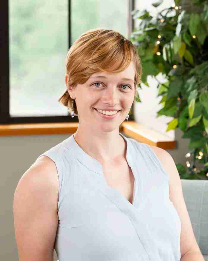 Grace Pernecky, LLMSW, EMDR and anxiety therapist in Michigan, smiling near a window with greenery behind her