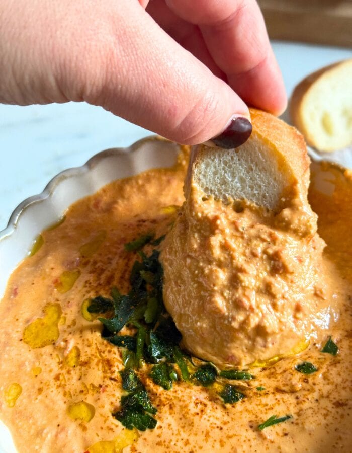Feta Paprika Dip - Easy & Quick Dip Recipe 5 paprika dip in a bowl, fingers holding a slice of bread dipping in the dip