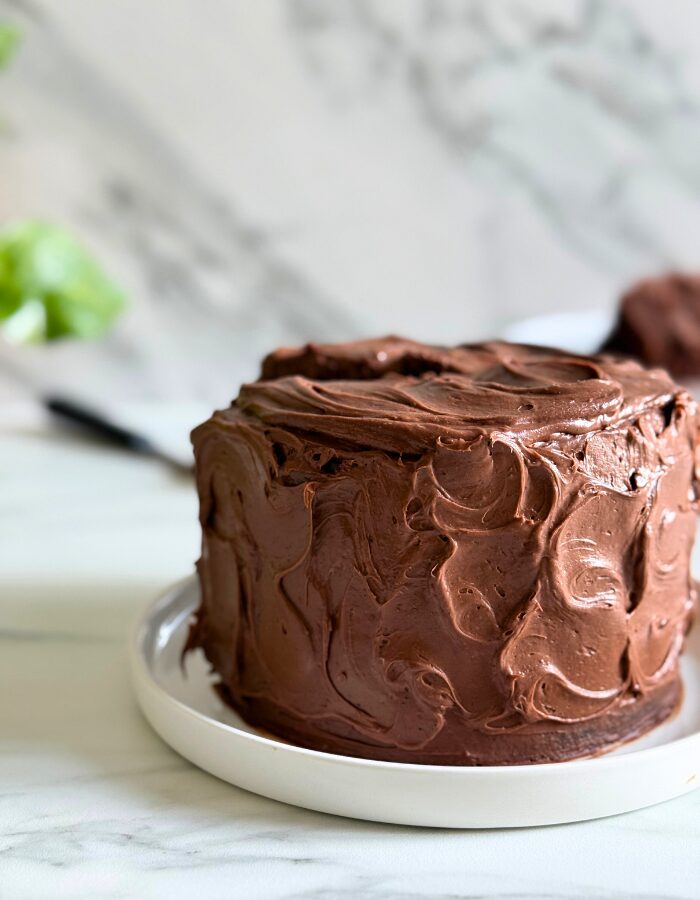 matilda's cake on a plate, a slice in the background, plant, on a marble background