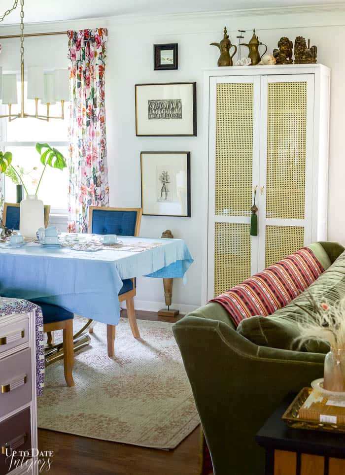 Living And Dining Rooms Divided by Rattan-Cane Cabinet. LIght blue tablecloth and dark blue dining chairs.