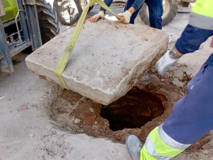 Operarios levantan una losa de piedra en las obras de la plaza de los Santos Niños de Alcalá de Henares
