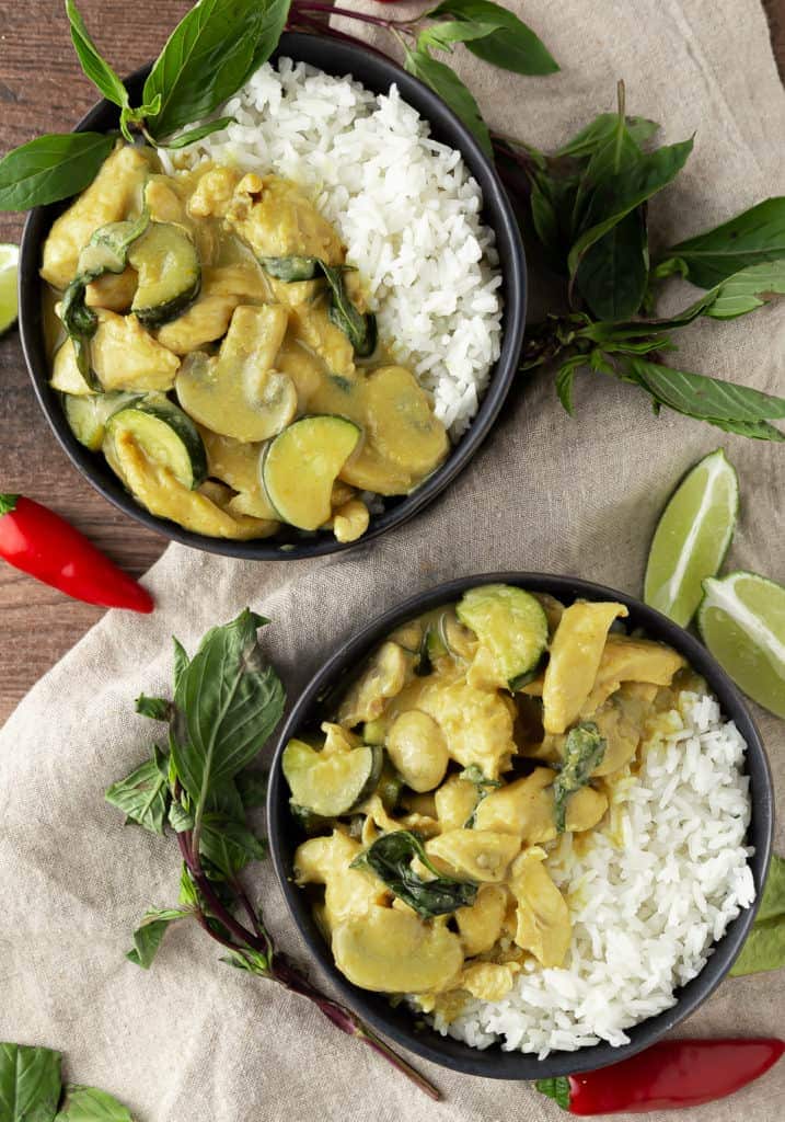 two bowls of thai green curry with chicken over rice