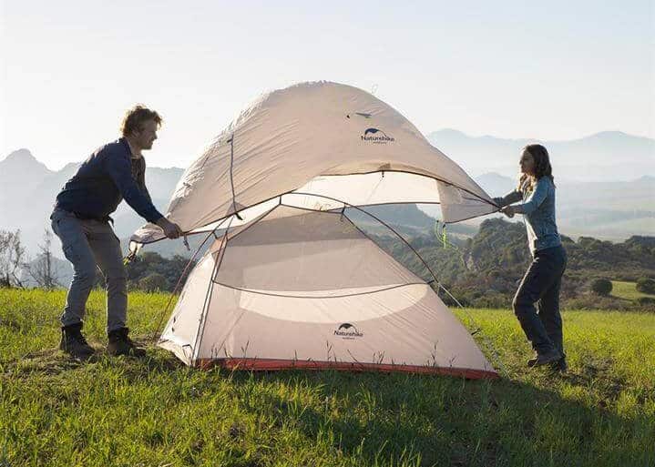 2 people putting the rainfly on a Naturehike cloud up tent