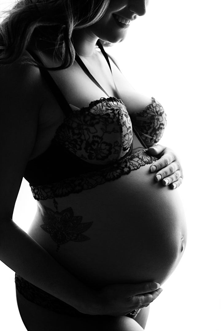 Eksplisitt gravidfoto av kvinne med gravid mage i svart hvitt, fokus på skjønnheten og roen i svangerskapet, perfekt for gravidfotografering og portretter under svangerskapet.