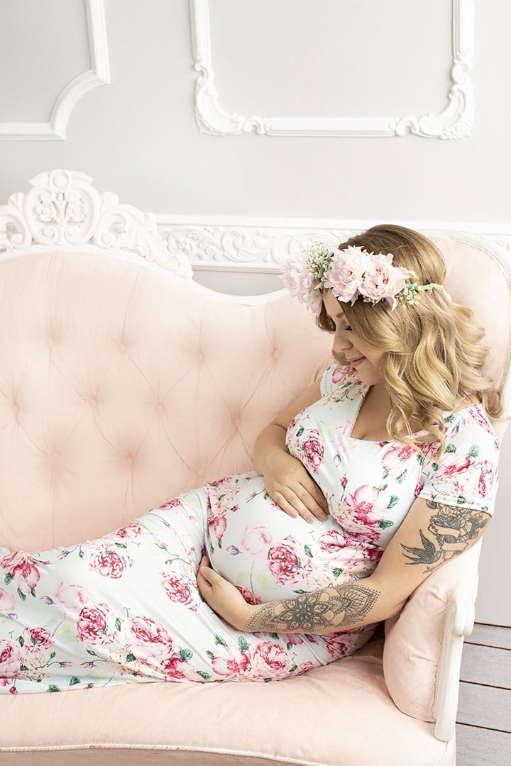 Aldri testament for pregnant woman in floral dress with flower crown sitting on pink vintage sofa.