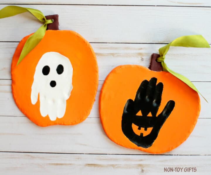 handprint Halloween keepsake craft for kids with a white ghost and black pumpkin