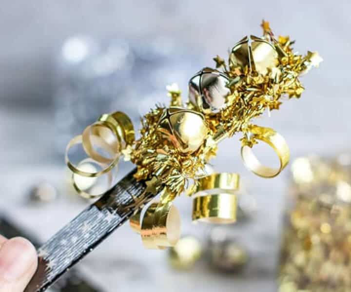 gold and silver noisemaker with popsicle stick in a child's hand