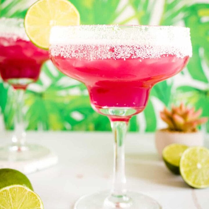 pink prickly pear margaritas surrounded by limes