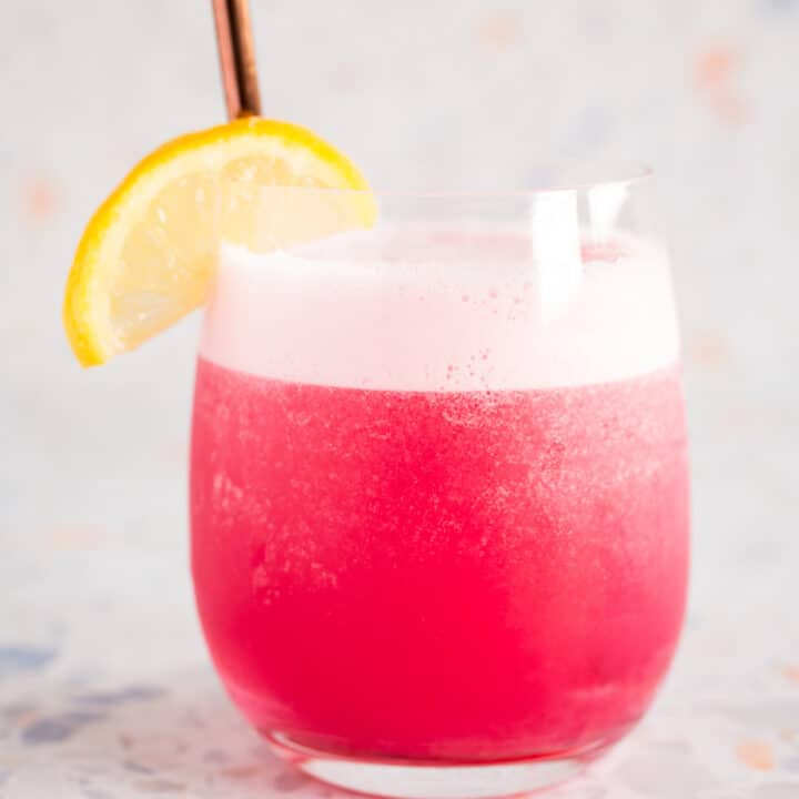 rhubarb gin fizz cocktail with lemon wedge garnish