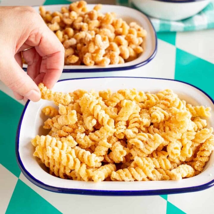 hand grabbing a piece of fried pasta out of a bowl