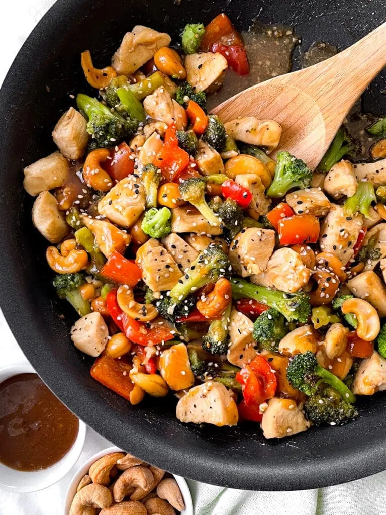 making the thai cashew chicken in a saucepan with cup of cashews to the side
