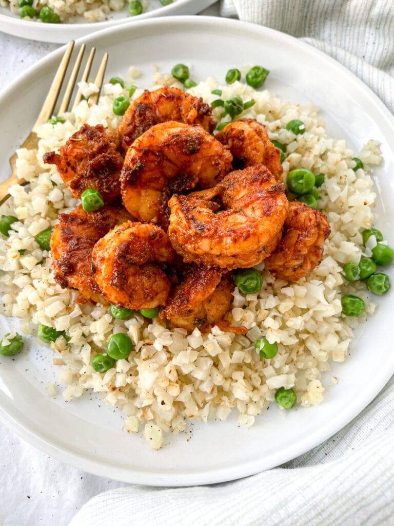 close up of blackened shrimp on cauliflower rice with peas