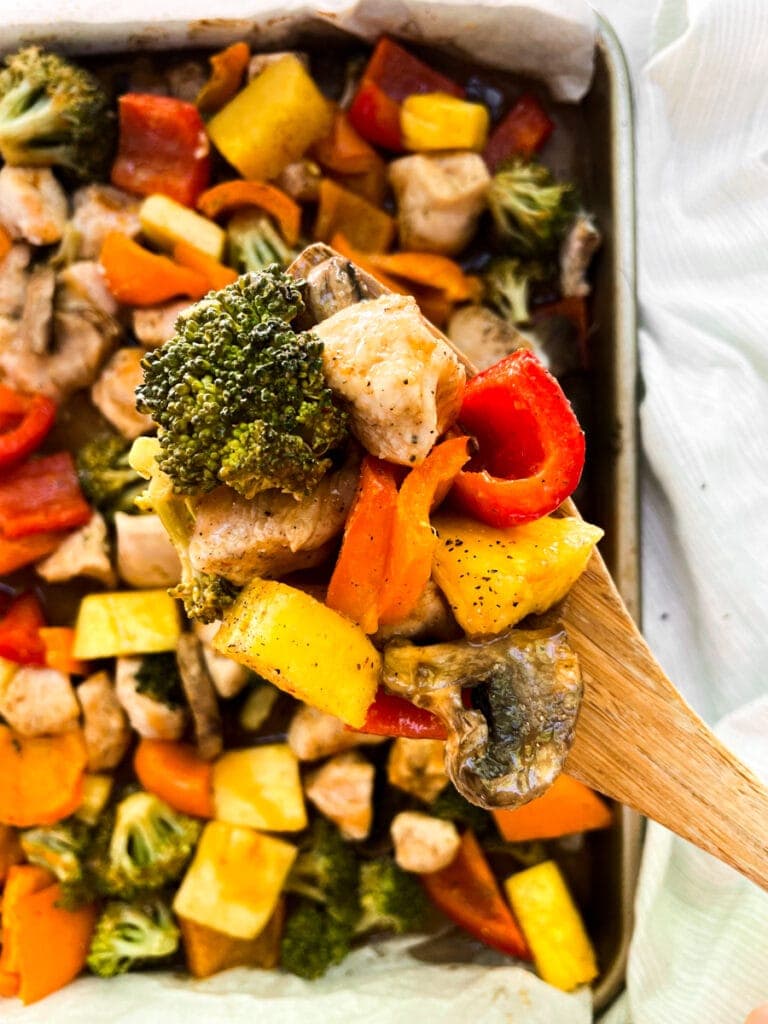 a scoop full of chicken and veggies on a wooden spoon