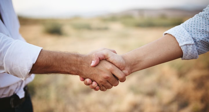 Deux humains se serrant la main sur un champ
