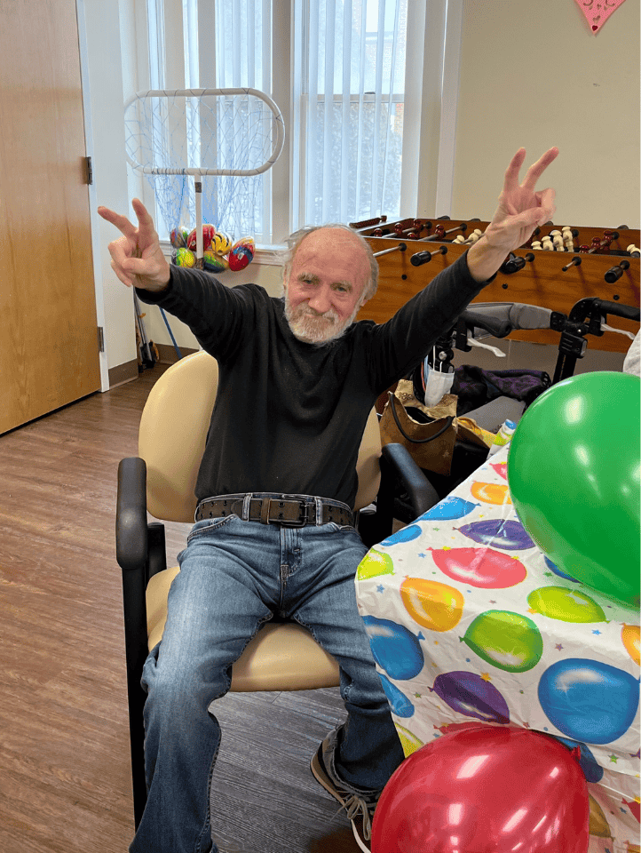 Senior man participating in birthday party with colorful balloons at Element Care PACE center