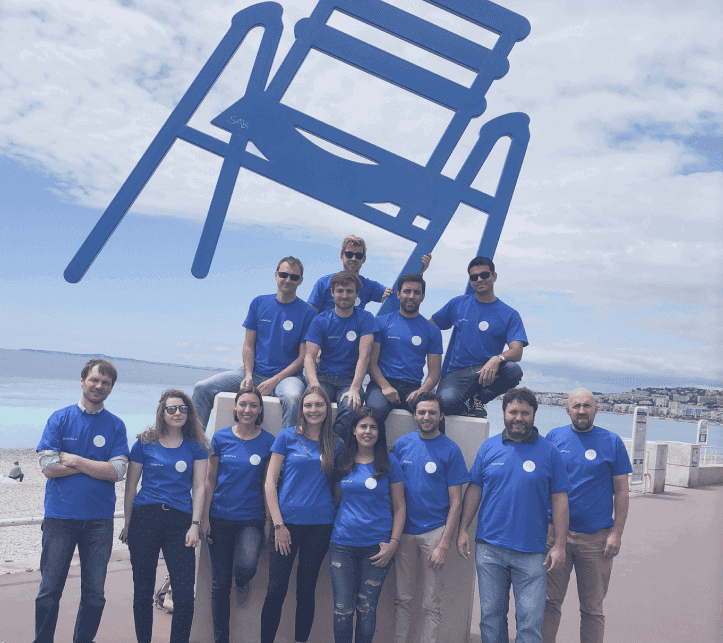 Diverse team of professionals at Quantilia by the waterfront with a giant chair sculpture.