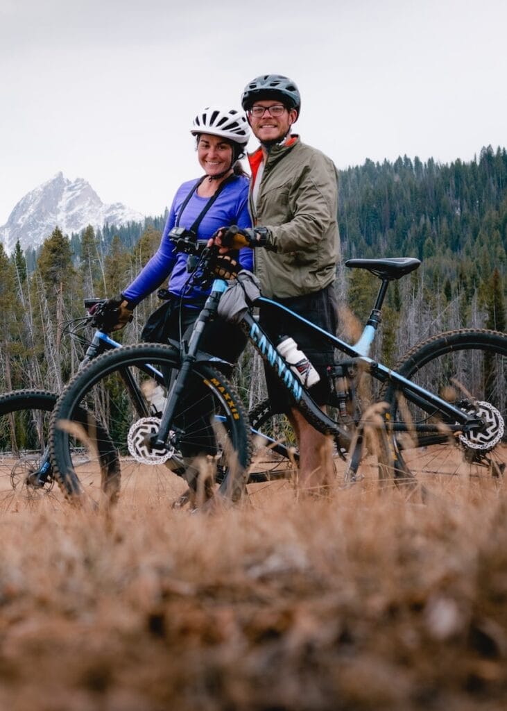 young couple pose holding their mountain bikes.