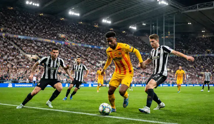 Alt= Newcastle – Barça à St James’ Park : duel entre un joueur du FC Barcelone et des défenseurs de Newcastle en Ligue des champions.