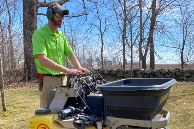 worker fertilizing lawn